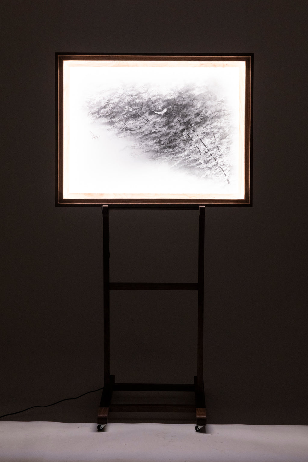Framed abstract artwork on a stand against a dark wall